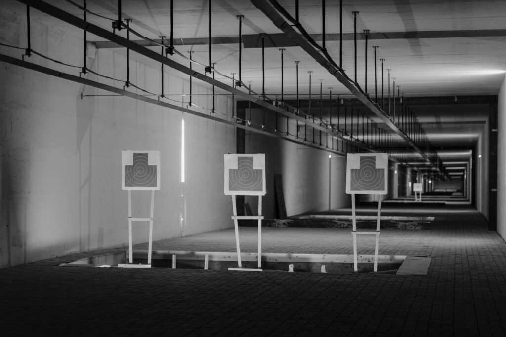 Indoor gun range with shooters at individual lanes, featuring digital targets and advanced ventilation systems.